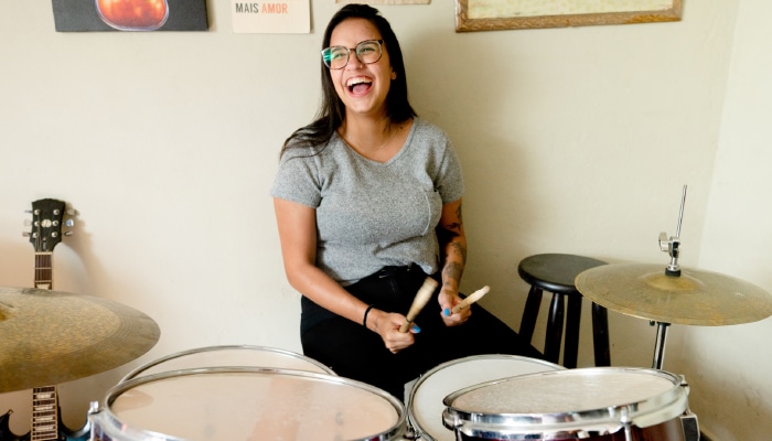 a woman smiling playing the drums
