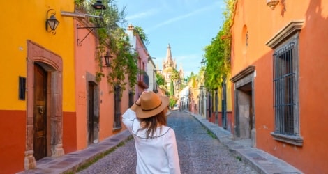 person in a hat walking down a colorful street
