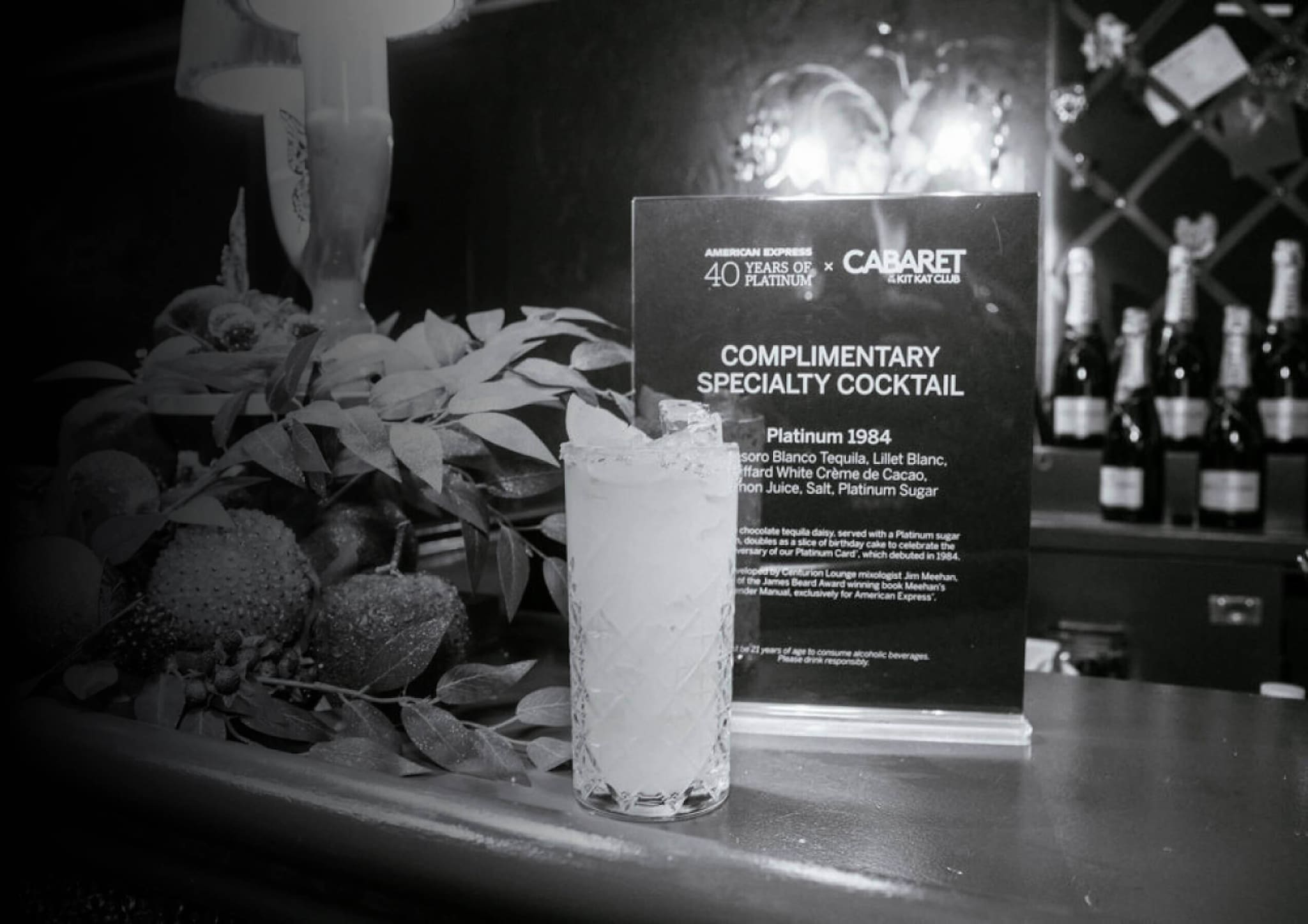 Image of a bar showcasing the complimentary Platinum 1984 cocktail with bottles of wine in the background