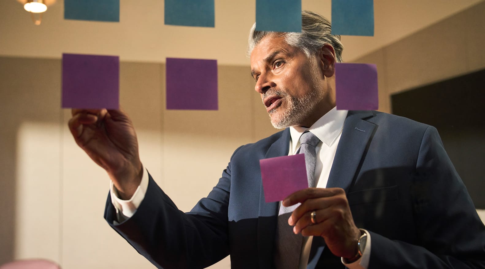 Businessperson organizing sticky notes on glass wall
