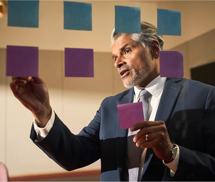 Businessperson organizing sticky notes on glass wall