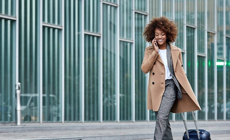Person on the phone walking with a suitcase