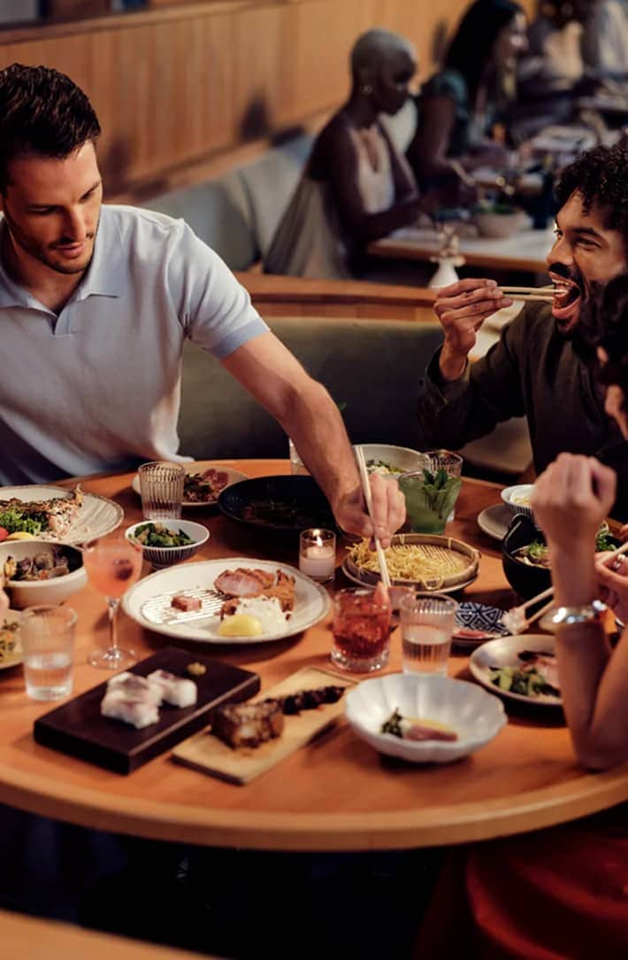 People enjoying dinner at a restaurant with Resy logo