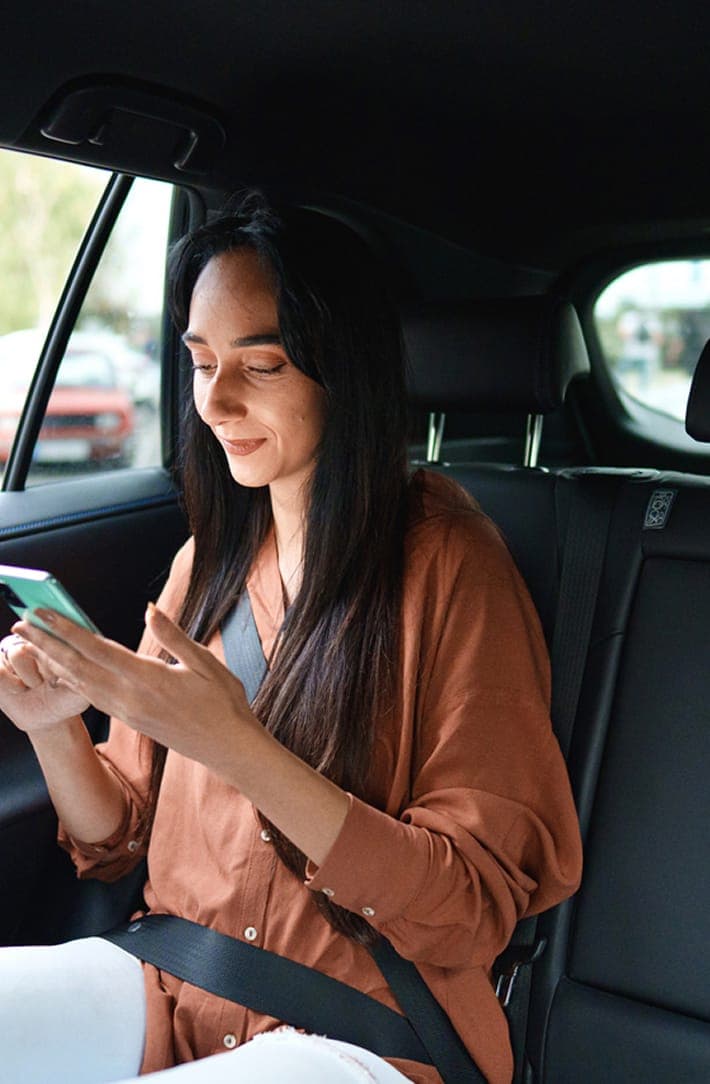 Person in the car on their phone with an Uber logo