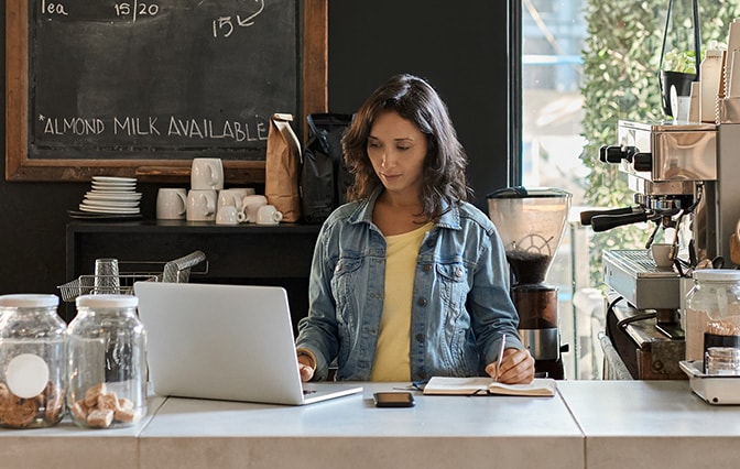 Barista standing at counter and looking at laptop