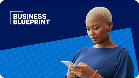 African American business owner against a blue background, checking her phone.