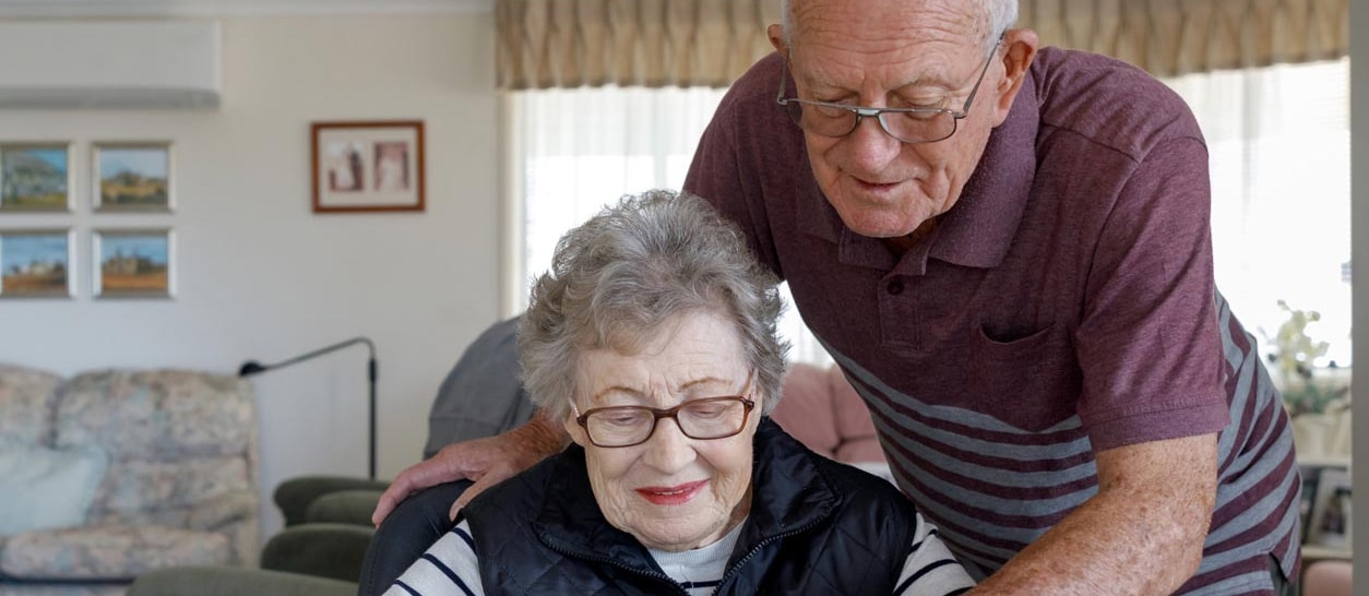 An older couple looking over a tablet at a table in their living room