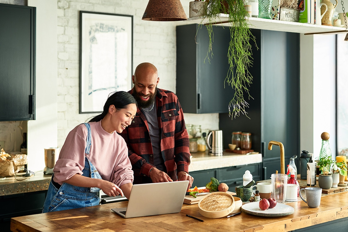 A couple using a laptop in a kitchen, engaged in checking debt to income ratio for mortgage