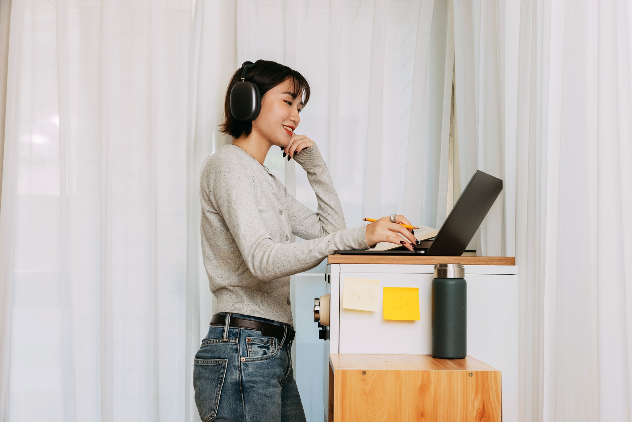 A woman wearing headphones and using a laptop.