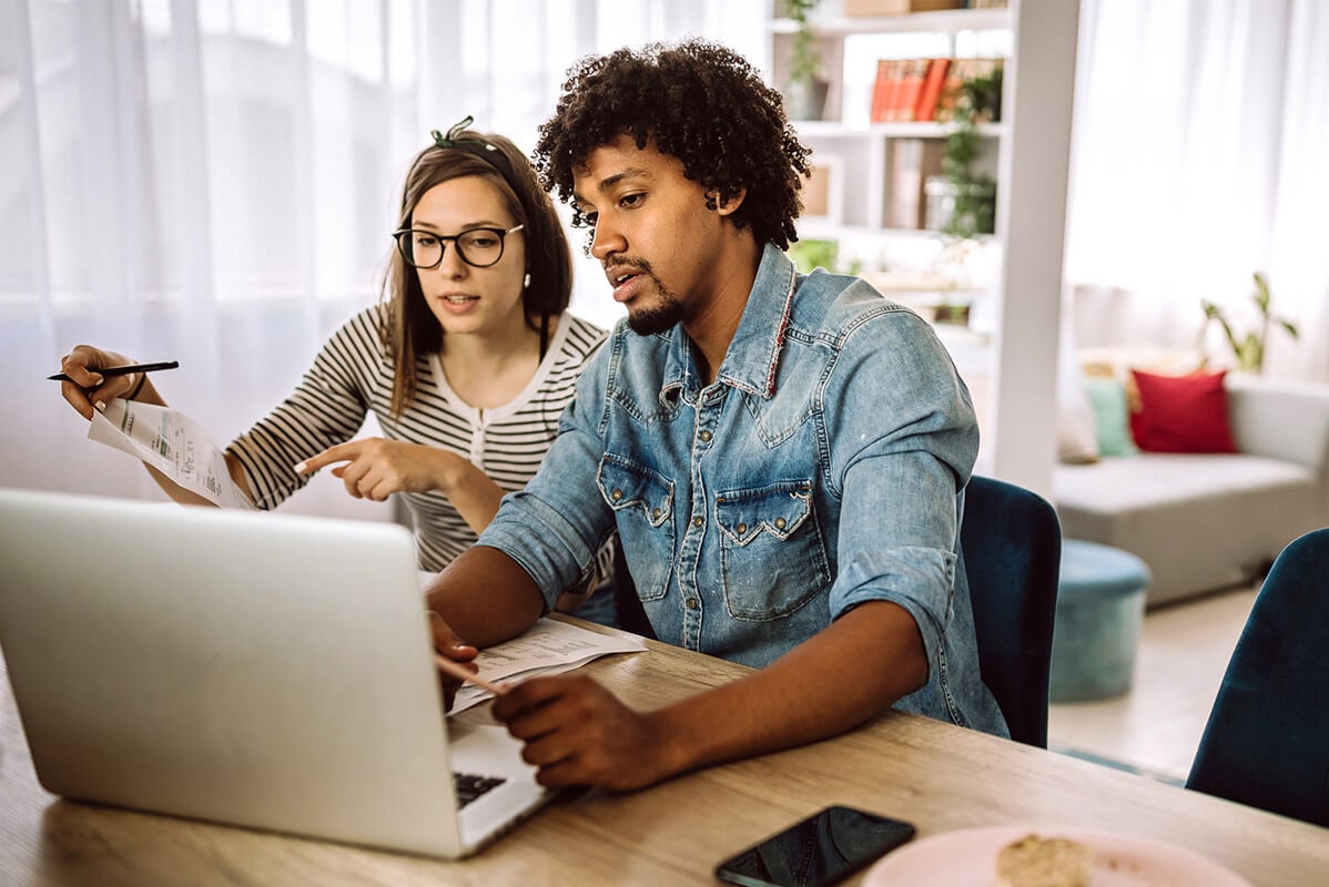 A couple sitting on a dining table with a laptop and discussing about loan to value ratio