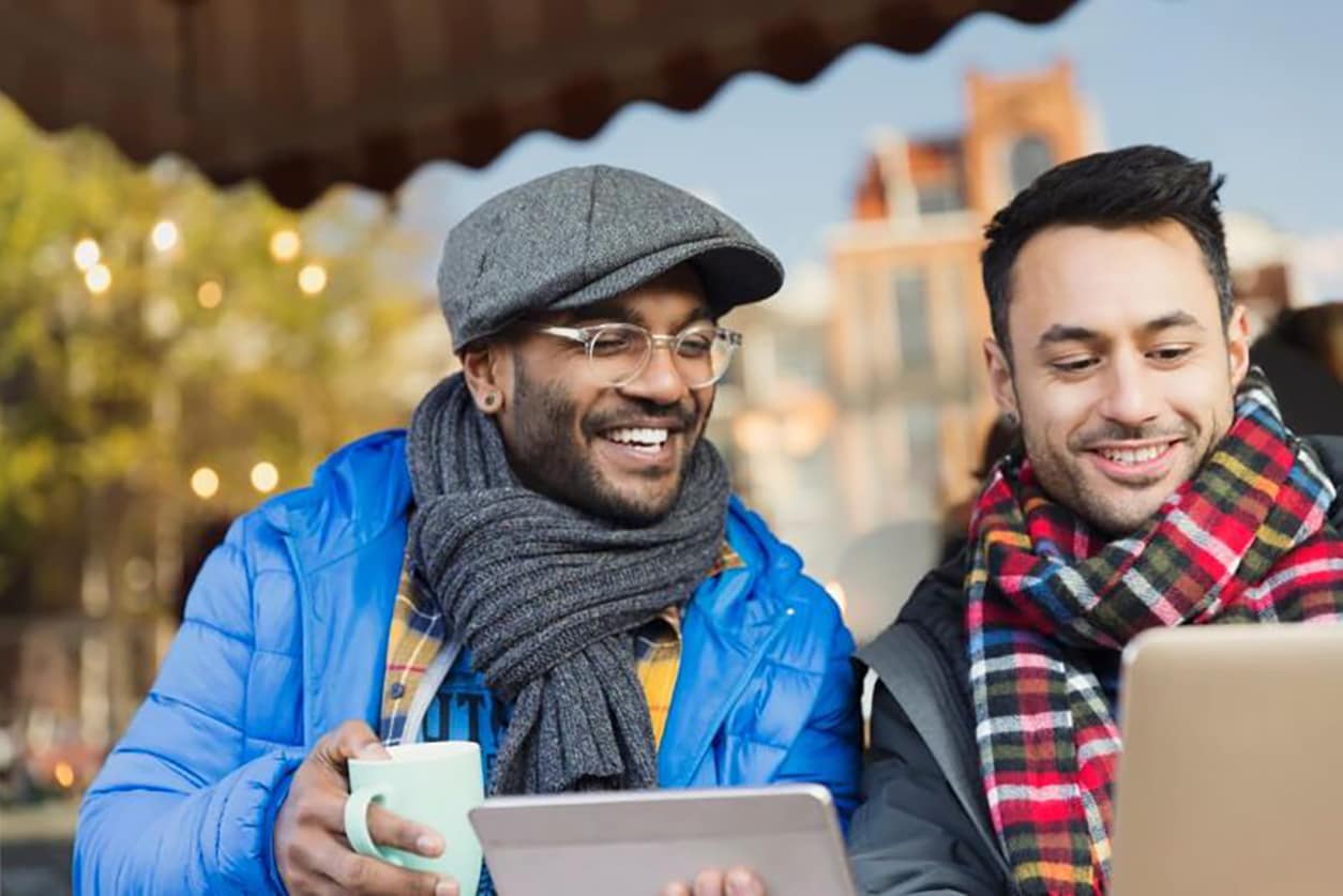 Two men seated on a bench, intently examining a tablet, discussing the significance of credit reports and their importance.