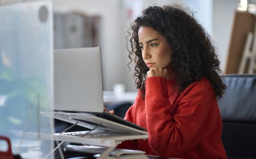 Woman sitting at desk looking at laptop
