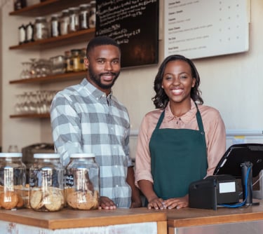 Two small business owners standing behind counter of café