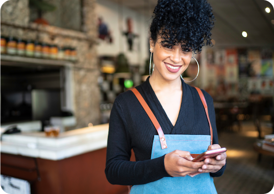 Business owner standing in shop and holding mobile device