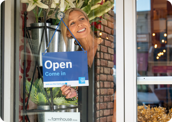 Business owner standing in shop window with Amex branded Open sign