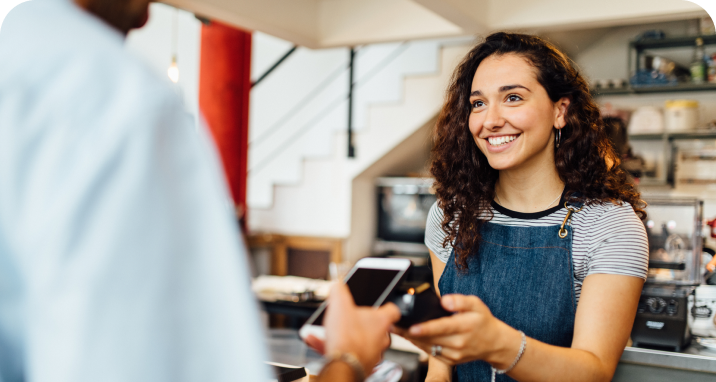 Small business merchant holding terminal up to customer paying with mobile device