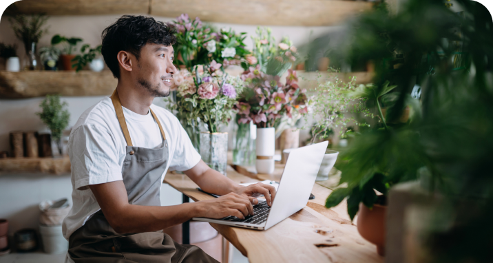 Floral shop owner sitting at desk and typing on laptop