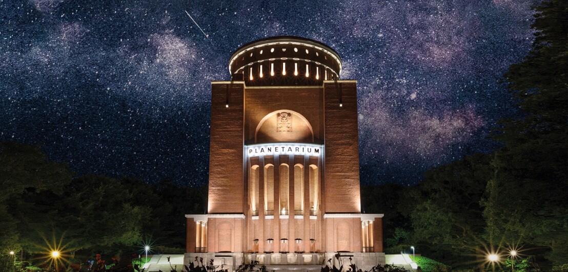 Das angeleuchtete Hamburger Planetarium, im Hintergrund ein Sternenhimmel