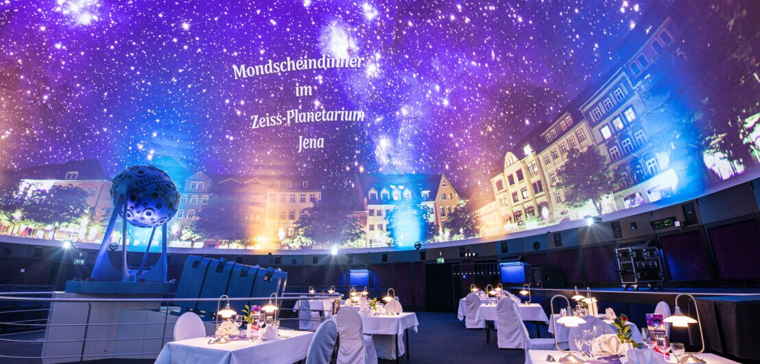 Sternenhimmel im Planetarium, im Vordergrund festlich eingedeckte Tische