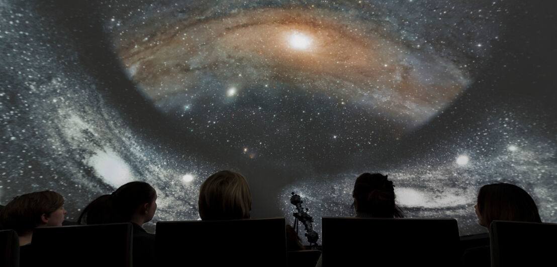 Zuschauer:innen im Planetarium, die in den Sternenhimmel schauen