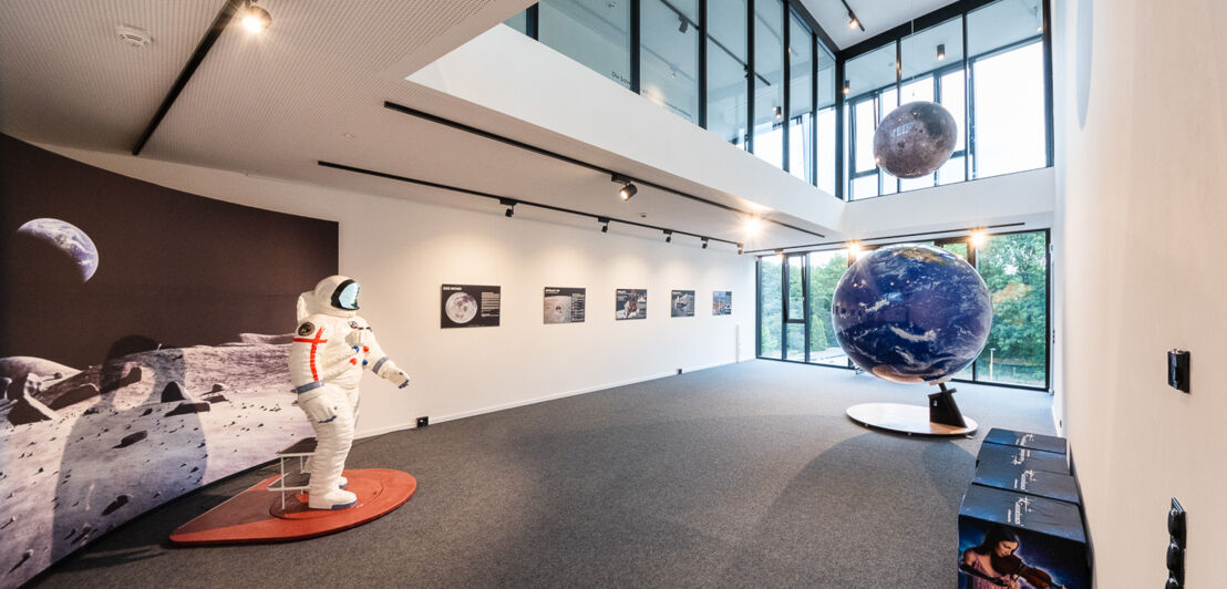 Ausstellungsraum, in dem Planetenmodelle, Bilder aus dem Weltall und ein Raumanzug zu sehen sind