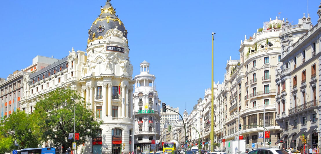 Blick auf die Gran Via in Madrid sowie das Metropolis-Gebäude mit einer geflügelten Victoria-Statue auf dessen Kuppel.