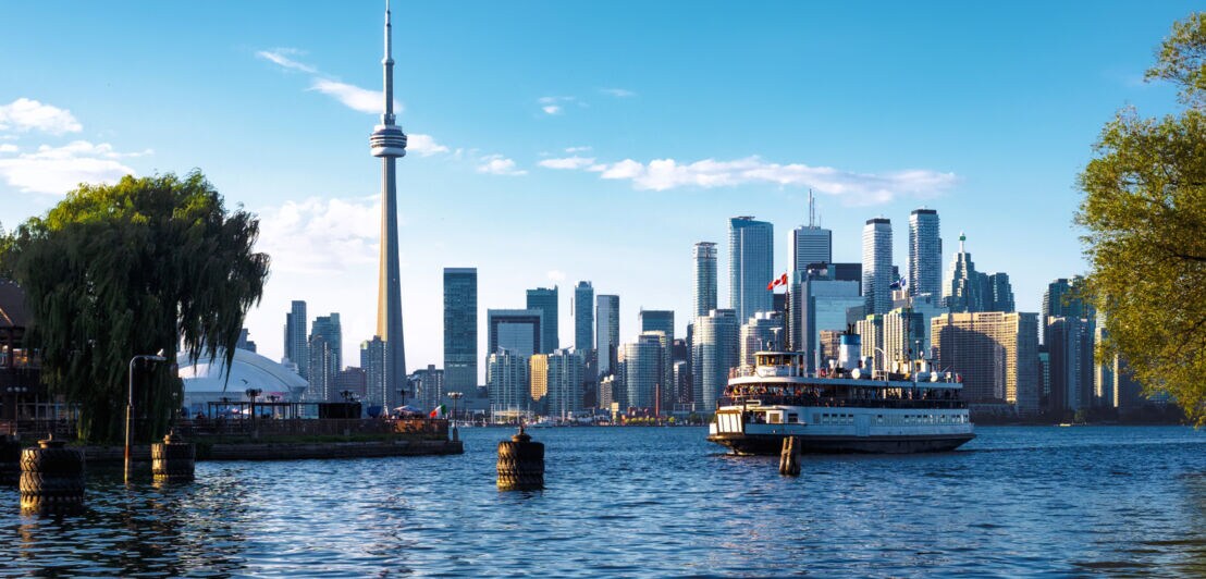 Blick auf die Skyline von Toronto mit dem bekannten CN Tower, im Vordergrund eine Fähre auf dem Wasser