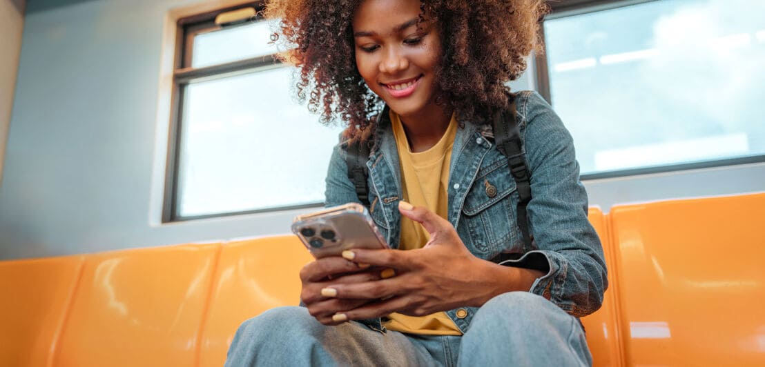 Junge Frau in der U-Bahn liest auf ihrem Smartphone