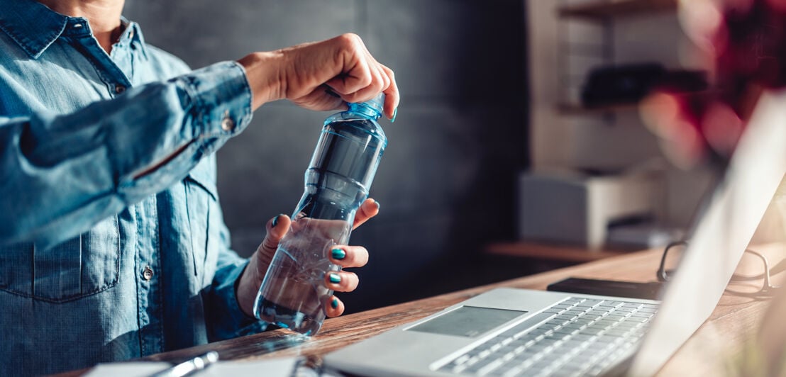Woman opening bottle of water in the office