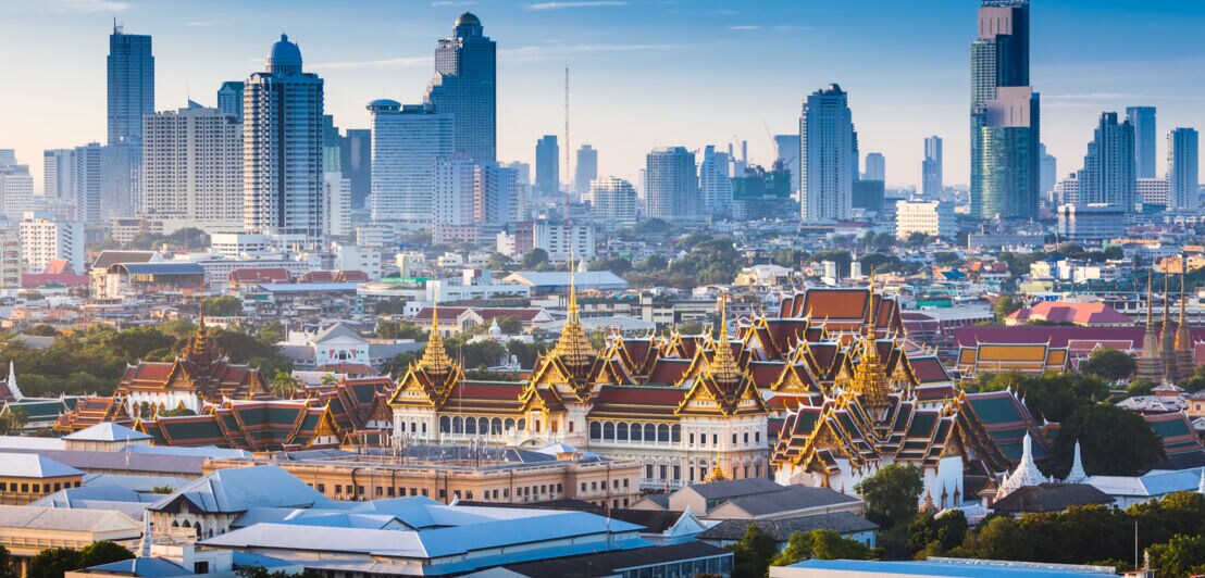 Stadtpanorama von Bangkok mit Königspalast vor einer Skyline mit Hochhäusern im Hintergrund.
