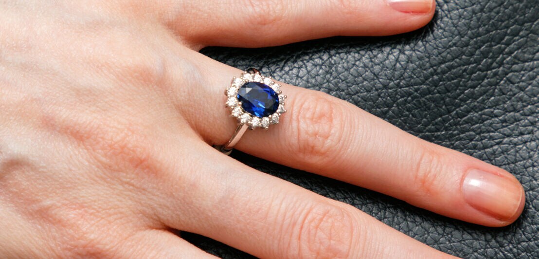 Ein Ring mit einem blauen Saphirstein an einer Frauenhand.