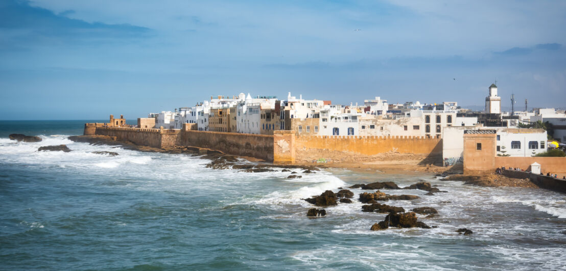 Stadt am Meer mit weißen Häusern im maurischen Stil, umgeben von einer Befestigungsmauer.