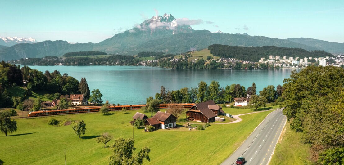 Landschaftspanorama mit Zug an einem See.