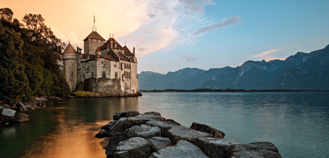 Mittelalterliche Burg am Ufer eines Sees bei Sonnenuntergang.