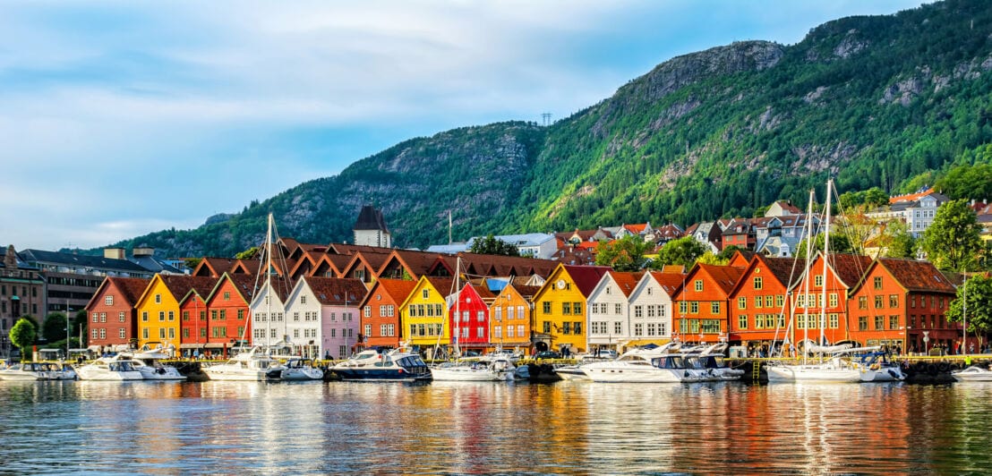 Hanseviertel mit bunten Häusern am Wasser vor Berglandschaft.