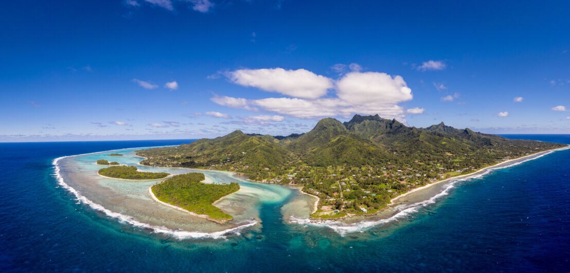 Luftaufnahme der Südseeinsel Rarotonga mit grüner Vulkanlandschaft und türkisblauer Lagune, umgeben von blauem Meer.