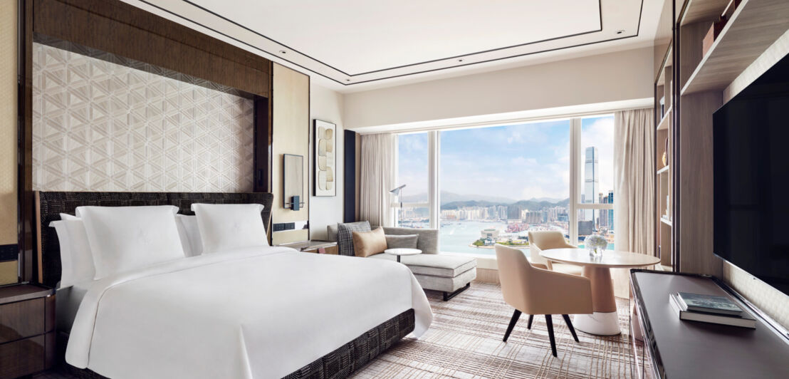 Luxuriöses Hotelzimmer mit Doppelbett und Panoramafenster mit Blick auf die Skyline von Hong Kong.