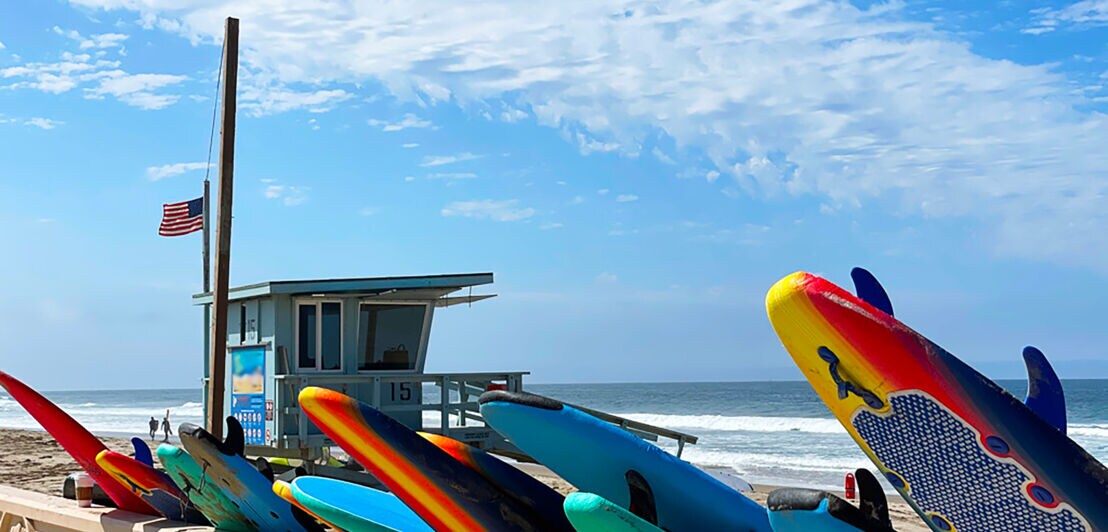 Bunte Surfbretter vor hellblauem Rettungsschwimmerturm am bekannten Zuma Beach in Malibu