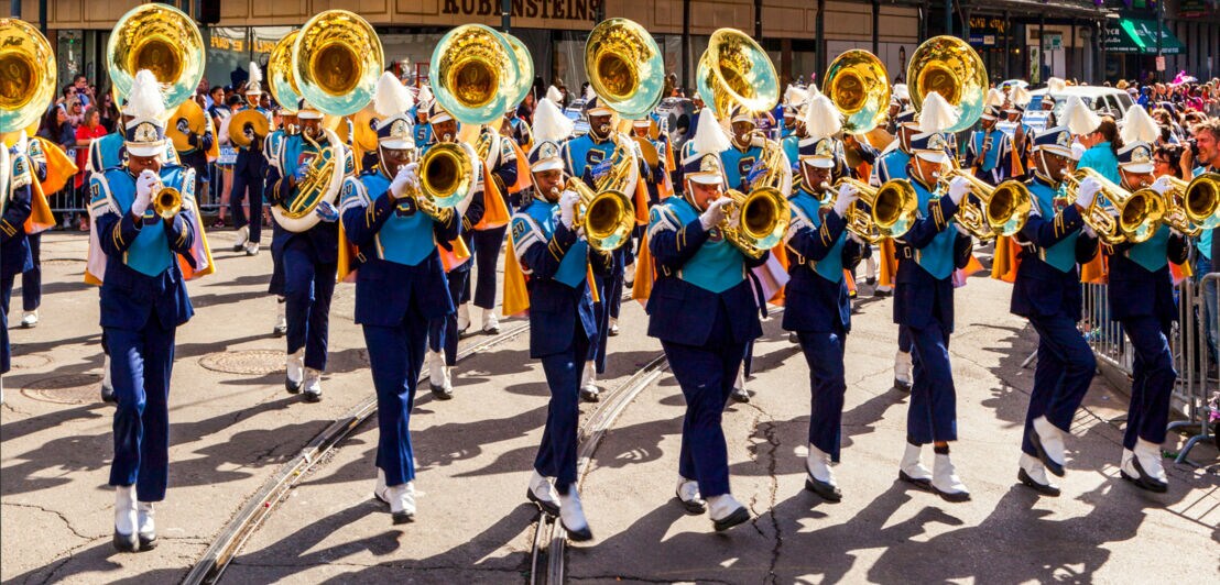 Eine Gruppe Musiker in blauen Uniformen mit Trompeten auf der Straße in einer Stadt.