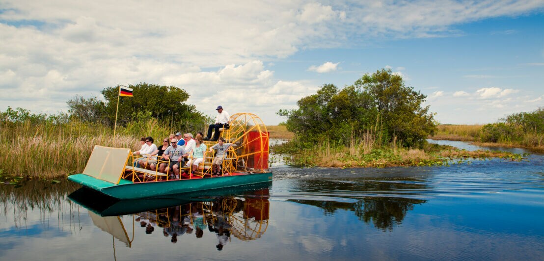 Personen auf einem Airboat in einem Sumpfgebiet.