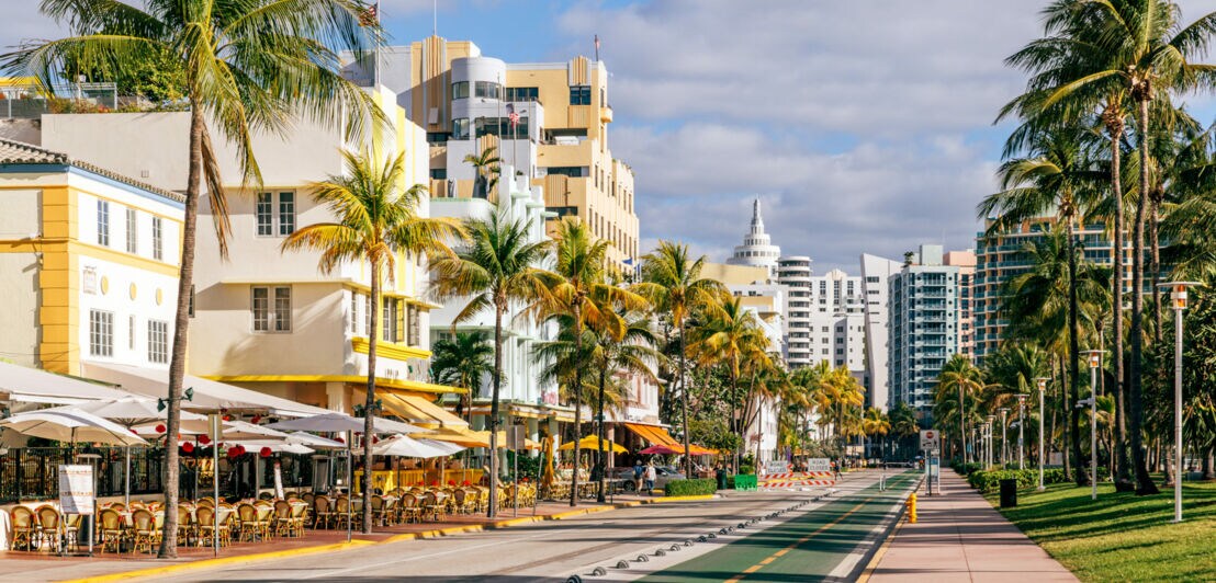 Palmengesäumte Promenade mit Art-déco-Gebäuden und Straßencafés.