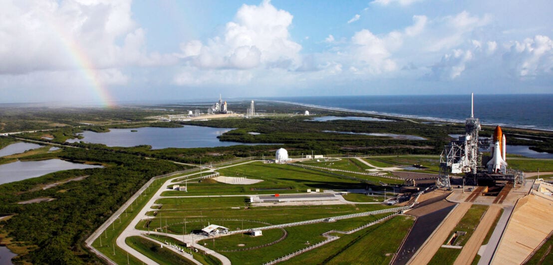 Weitläufiges Areal mit Raketenstartplatz, umgeben von Grünflächen am Wasser.