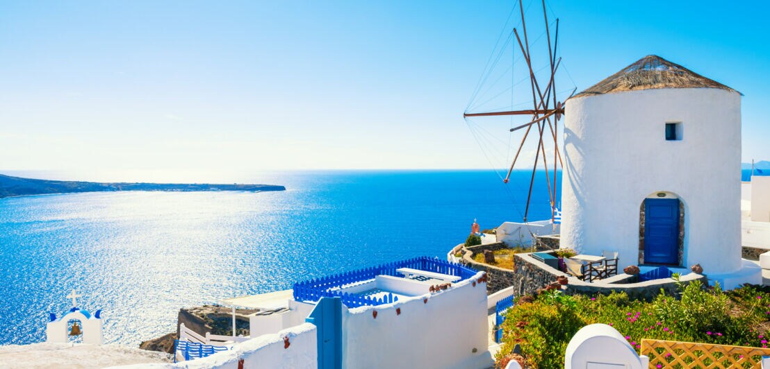 Weiße Windmühle in Oia, im Hintergrund das blaue Meer und der Himmel.