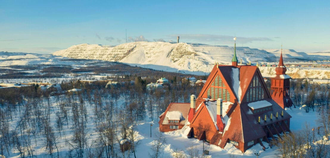 Rote Holzkirche im skandinavischen Stil in Schneelandschaft.