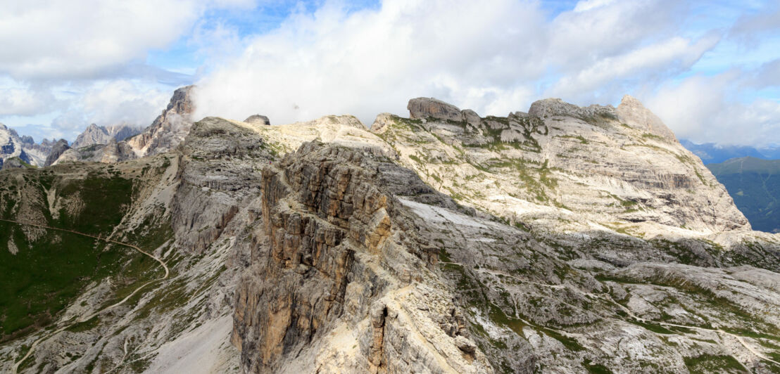 Blick auf eine karge Berglandschaft, blauen Himmel und weiße Wolken in den Dolomiten. 