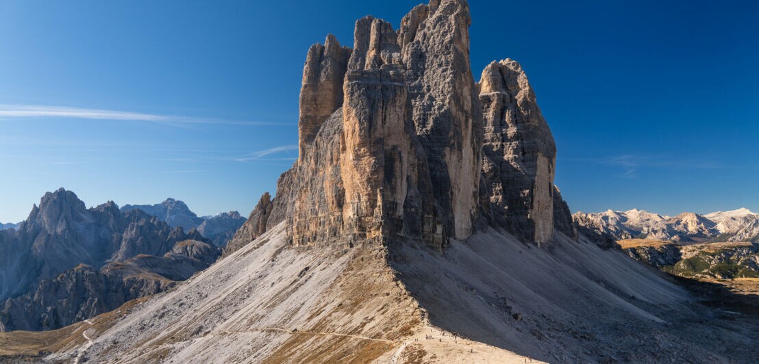 Blick auf markante Felstürme in den Dolomiten, im Hintergrund blauer Himmel.