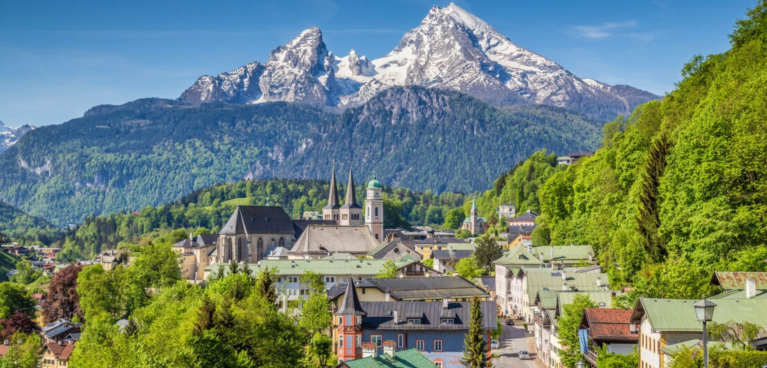 Stadt Berchtesgaden mit schneebedecktem Gipfel des Watzmanns im Hintergrund.