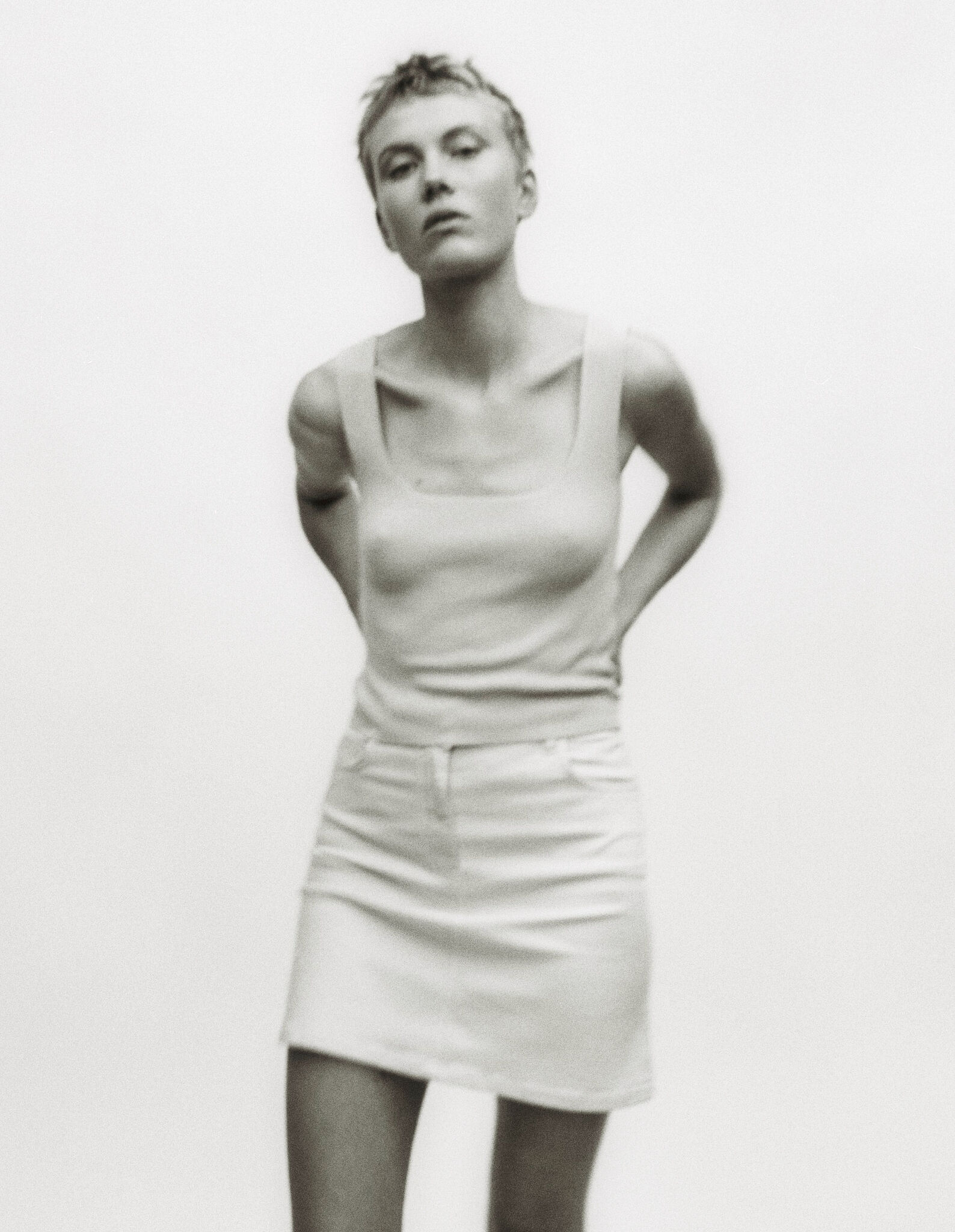 Schwarz-weiß-Fotografie einer Frau in kurzem, hellem Jeansrock und Top.