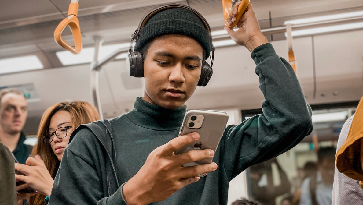 Junger Mann in der U-Bahn liest auf seinem Smartphone