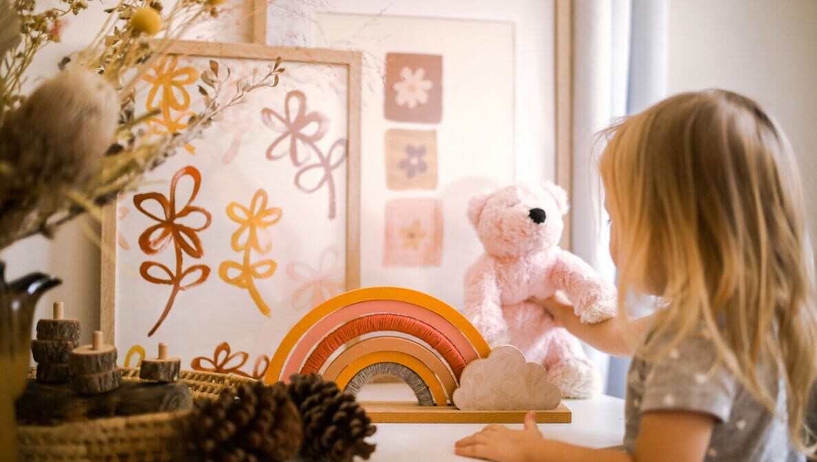 Ein kleines Kind mit einem Teddy und Holzspielzeug